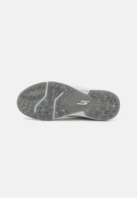 Skechers shoe outsole with a grey rubber surface, featuring a textured design of hexagonal lugs for traction and supportive grooves.