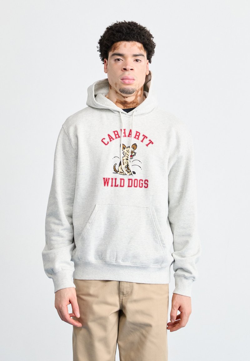 Sudadera gris con bolsillo delantero, con el texto "Carhartt Wild Dogs" y una ilustración de un perro. Tejido suave, capucha con cordón ajustable.