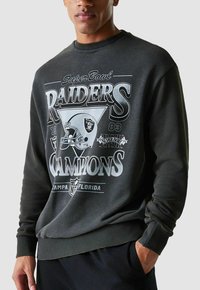 Felpa nera con grafica "Super Bowl Raiders Champions", stampa bianca e design del casco. Polsini e fondo a costine, vestibilità comoda.