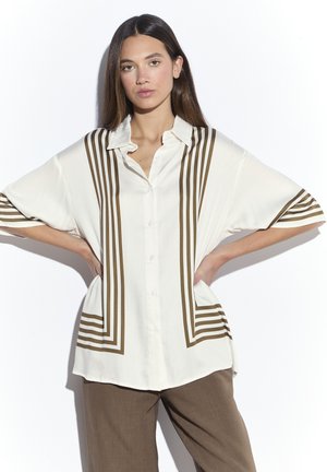 Biała koszula z brązowymi pionowymi paskami, krótkimi rękawami i kołnierzykiem. Luźny krój z zapięciem na guziki i bocznymi kieszeniami. Miękka w dotyku.