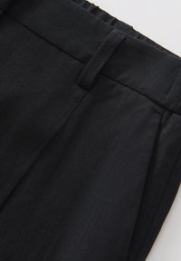 Black tailored trousers made from a textured fabric, featuring a flat front, waistband with belt loops, and visible pleats.