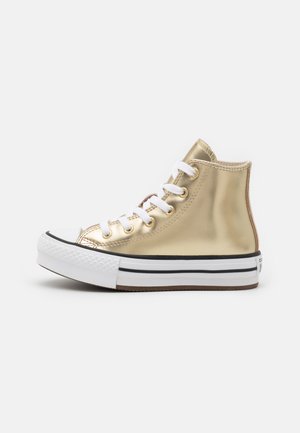 Sneaker alta dorata con suola in gomma bianca, dettagli neri e occhielli metallici. Finitura metallizzata liscia; design tradizionale con lacci.