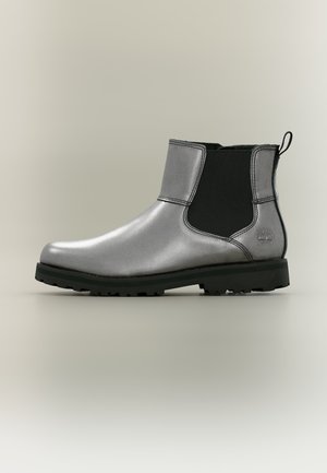 Bottine en cuir argenté avec des panneaux latéraux élastiques noirs et une semelle en caoutchouc noire, avec une languette à l'arrière.