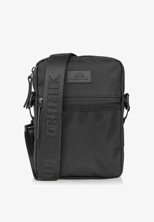 Czarna torba na ramię wykonana z trwałej tkaniny. Posiada teksturowany przód, kieszenie zapinane na zamek oraz szeroki, regulowany pasek z logo.