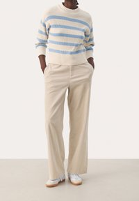 Striped sweater with light blue and cream colors, paired with beige corduroy wide-leg pants. Model wears white sneakers with tan soles.