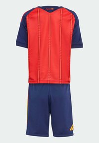 Červený a námornícky modrý futbalový dres s horizontálnymi pruhmi a nápisom "España". Zodpovedajúce námornícky modré šortky so žltým logom Adidas na boku.