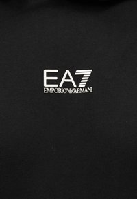 Juodas džemperis su baltu „EA7 Emporio Armani“ logotipu. Lygios tekstūros, reguliarios priliečiančios formos su raištais apvadu prie kaklo.
