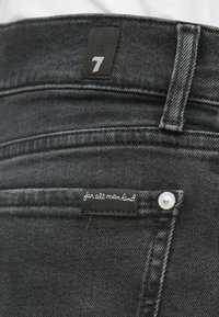 Tumehallist teksariidest püksitasku musta sildiga, kus on kirjas "for all mankind", ning väike must silt numbriga 7 vöökoha lähedal.