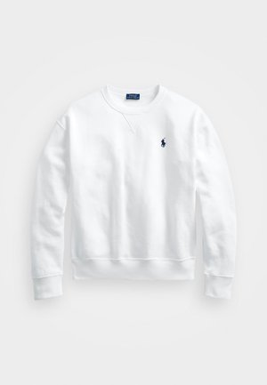 Hvit bomullsgenser med rund hals, lange ermer, ribbestrikkede mansjetter og nederkant. Har en liten marineblå polo-logo på venstre bryst.