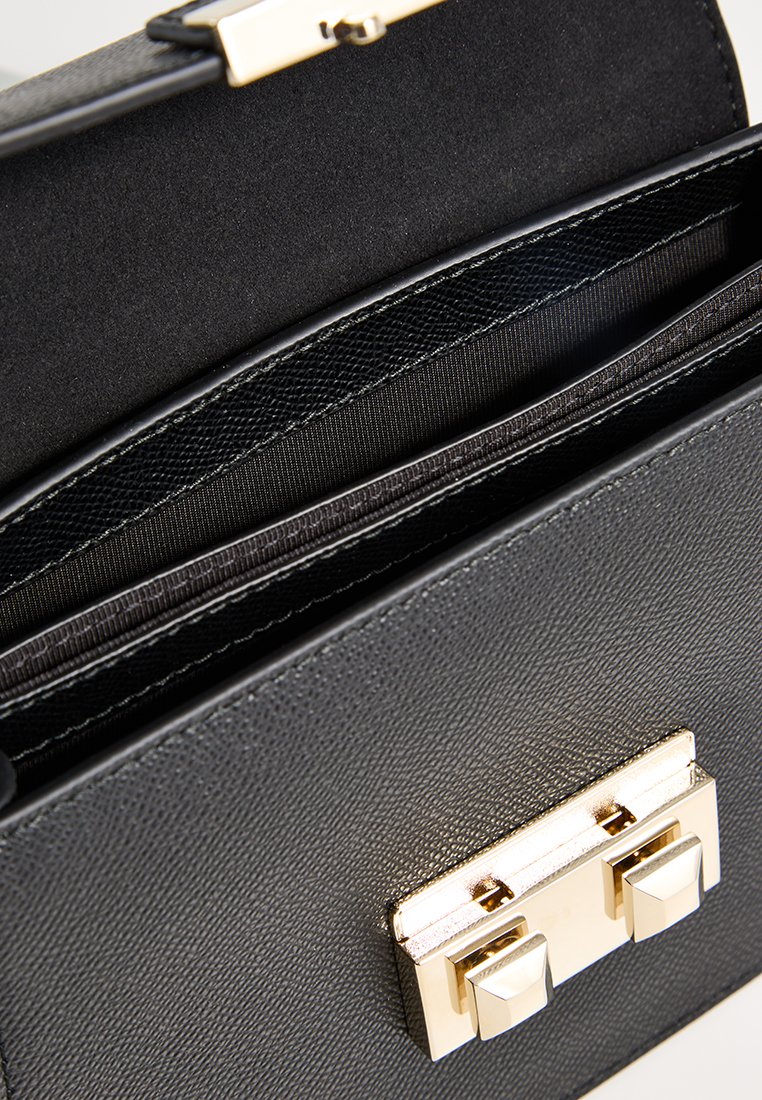 Schwarze Ledertasche mit glatter Textur, Verschluss mit goldfarbener Hardware und mehreren Innenfächern zur Organisation.