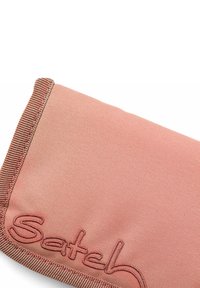 Roze tekstuurstof zakje met gestikte randen. Bevat een geborduurde merknaam in een iets donkerdere roze tint, wat getuigt van een schoon ontwerp.