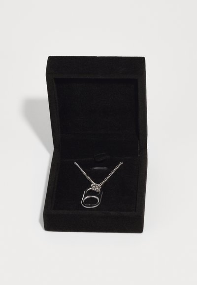 Collana in metallo argentato con un unico pendente a doppio anello, presentata in una scatola di gioielli in velluto nero con un morbido interno.