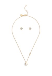 Set di gioielli in tonalità oro, composto da una delicata collana a catena con un pendente rotondo e orecchini a bottone, ciascuno decorato con una pietra trasparente.