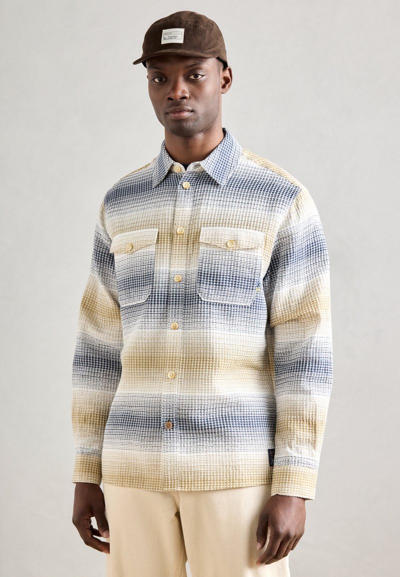 Kariertes Flanellhemd mit Knopfleiste in Blau, Gelb und Weiß, ausgestattet mit zwei Brusttaschen und braunen Knöpfen.