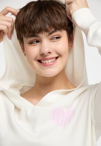 Witte hooded sweater met een zachte textuur, voorzien van een roze gebreid hartdetail op de borst en geribbelde manchet.