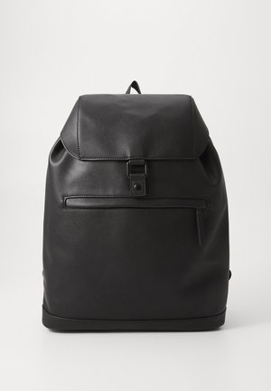 Mustmust nahk seljakott volditud ülaäärega, esiotsa tõmblukuga taskuga ja siledast tekstuurist. Omab lihtsat disaini, kus ei ole nähtavat brändimist.