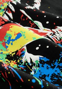 Bunt gemustertes Stoff mit schwarzem Hintergrund; zeigt leuchtend rote, gelbe, grüne und blaue Akzente in abstrakten Designs.