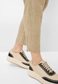 Sneakers con un upper in tessuto fantasia di un rosa chiaro e beige, dettagli in pelle nera e una suola piatta bianca con texture.