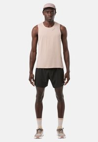 Light beige sleeveless athletic top with textured fabric and black shorts. Paired with a matching cap and shoes with beige, gray, and white accents.