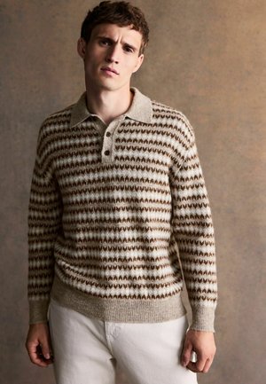 Knit sweater with a beige and brown geometric pattern, collared design, and three buttons on the front, paired with light-colored pants.