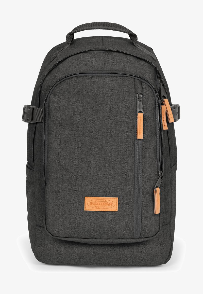 Svart tygryggsäck med en slät textur, som har en framficka, dragkedjeslutningar och orange läderdetaljer. Polstrade remmar och ett handtag på toppen.