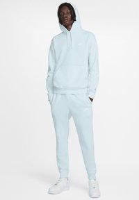 Felpa blu chiaro con tasca a marsupio, polsini e orlo a coste, abbinata a pantaloni della tuta coordinati con un piccolo logo e vita elasticizzata.