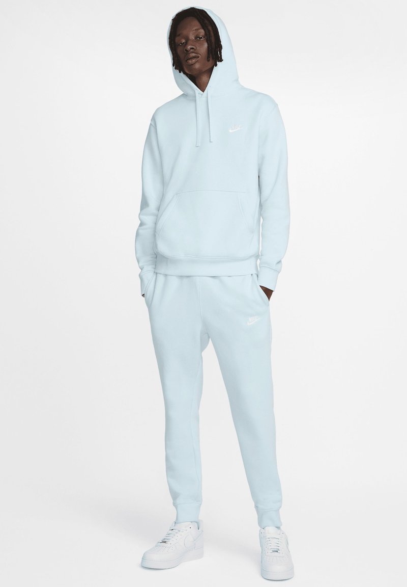 Sudadera azul claro con bolsillo canguro, puños y dobladillo acanalados, combinada con pantalones de chándal a juego que presentan un pequeño logo y una cintura elástica.