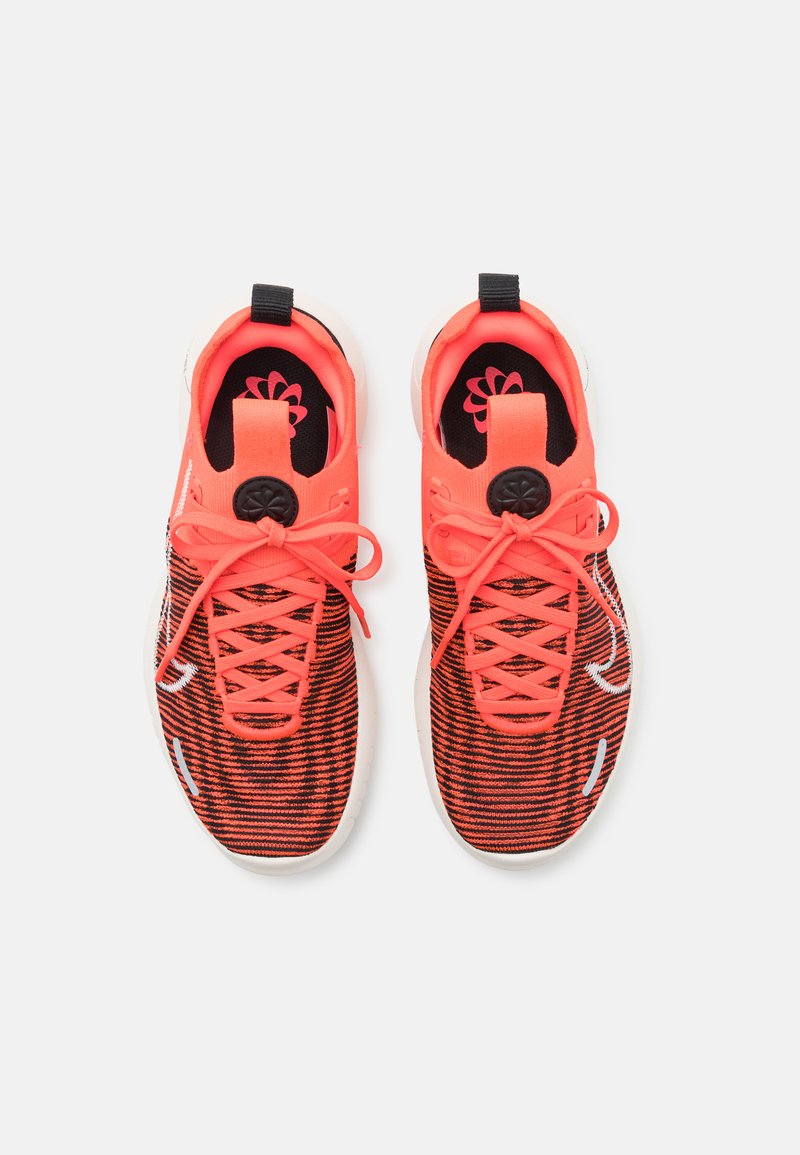 Sport Sneakers mit einem Obermaterial aus schwarz-rotem Streifenstoff, leuchtend orangefarbigen Akzenten, runden Schnürsenkeln und einer weißen Sohle mit einem dezenten Logo.