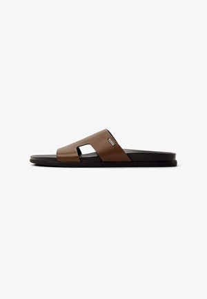 Brown synthetic slide sandal with a wide, open toe design, featuring cut-out accents. Black sole provides a flat and relaxed fit.