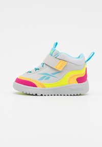 Gray athletic shoe with vibrant pink, yellow, and turquoise accents. Features a strap, textured sole, and Reebok logo.
