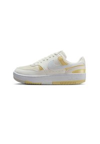 Zapatillas blancas con acentos amarillos, fabricadas con materiales de malla y cuero, puntera redonda, suela plana y diseño de cordones.