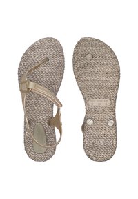 Beige sandalen met een getextureerde touwzool, verstelbare band en ronde hardware accenten. De voetbed heeft een reliëf met letters.