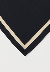 Tela negra con un borde beige, doblada para mostrar una esquina recta sobre un fondo blanco.