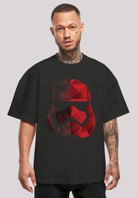 Černé tričko s geometrickým designem helmy Stormtroopera v červené barvě, se zaoblenými tvary a kontrastními detaily na helmě.