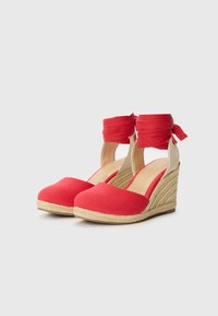 Röda canvas espadriller med kilklack. Har ankelsnören, jute repdetaljer och en rundad tådesign. Mjuk, strukturerad ovandel.