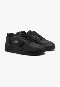 Zapatillas de cuero negras con acentos texturizados, cuello acolchado y suela de goma negra. Presentan un pequeño logo verde en el lateral.