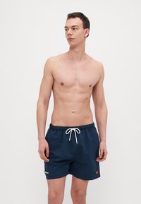 Herre svømmebukser i marineblått, laget av lett materiale, med elastisk midjebånd, hvit snor og en liten logodetalj på venstre ben.