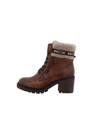 Bottine marron avec talon épais, col en shearling, fermeture éclair latérale, lacets et sangle de marque "Mustang" autour du haut.