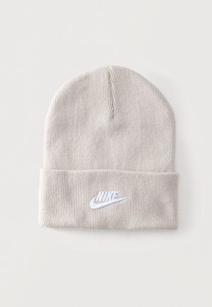 Gorro de punto gris claro con ala doblada que presenta un logo de Nike bordado en blanco sobre un fondo blanco liso.