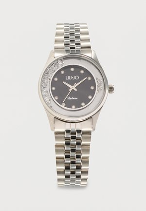 Silver metal wristwatch with black dial, crystal hour markers, and decorative crystals inside the transparent watch face.