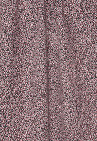 Tissu noir avec un motif géométrique de hexagones en rouge et blanc, avec une légère texture, tombant en douceur.