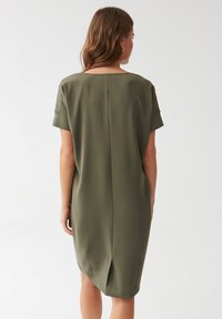 Olive green, knee-length dress made of smooth fabric. Features short rolled sleeves and a straight cut with a center back seam.
