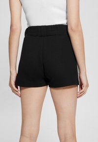 Shorts neri in cotone con una cintura elastica, caratterizzati da una semplice e liscia texture e una vestibilità classica e rilassata.