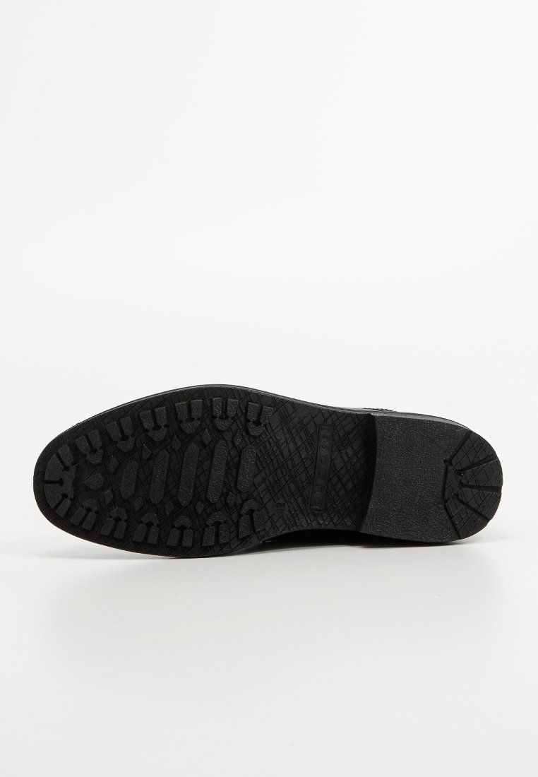 Semelle en caoutchouc noir avec des crampons profonds, présentant un motif texturé et une pointe arrondie. Matériau durable conçu pour l'adhérence et la stabilité.