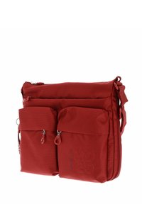 Sac à épaule en tissu rouge avec une surface texturée, comportant deux poches zippées à l'avant, un compartiment principal zippé et une bandoulière réglable.