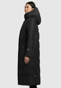 Schwarze Pufferjacke mit Kapuze, ausgestattet mit einem gesteppten Design, seitlichem Reißverschlussfach und Logo-Akzenten. Der Stoff wirkt glatt und isoliert.