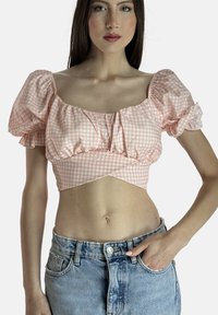 Top corto in gingham rosa con maniche a palloncino, caratterizzato da un scollo quadrato e dettagli arricciati, abbinato a pantaloni corti di jeans a vita alta.