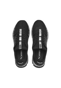 Baskets de sport en mesh noir avec des accents blancs, un design flexible et des lacets. Comprend des éléments de marque et une semelle texturée.
