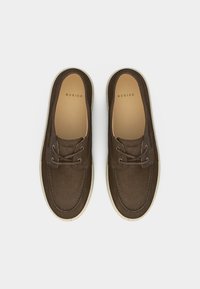 Καφέ καστόρινες casual παπούτσια με κορδόνια και μπεζ σόλες, από ψηλά, με την επωνυμία "Nubikk" στα πέλματα και τη γλώσσα.