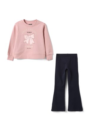 Pinkes Sweatshirt mit langen Ärmeln, Schleifengrafik und Text, kombiniert mit schwarzen ausgestellten Hosen auf weißem Hintergrund.